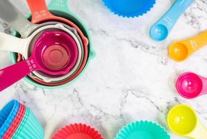 impostato di misurazione tazze, misurazione cucchiai e Cupcake silicone muffe uso nel cucinando posare su marmo tavolo foto