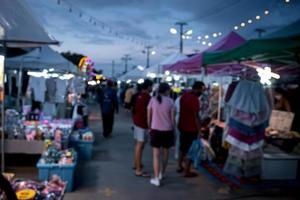 sfocato Immagine di notte mercato Festival persone a piedi su strada con leggero bokeh per sfondo. foto