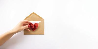 un' donna inserti il rosso cuore in il lettera per san valentino giorno. bandiera foto