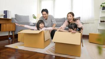 asiatico famiglia marito e moglie e bambini con cartone scatole avendo divertimento su in movimento giorno, mutuo, prestito, proprietà e assicurazione concetto.