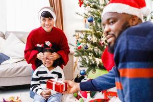 famiglia afroamericana che sorprende con un regalo il giorno di natale. buon Natale. foto