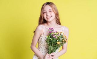 immagine di giovane donna asiatica con fiori su sfondo giallo foto