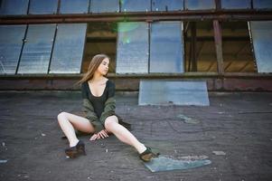 ragazza modello sexy con gambe lunghe in lingerie nera vestito corpo costume da bagno combidress e giacca poste sul tetto di un luogo industriale abbandonato con finestre. foto