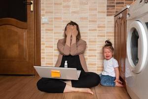 la giovane bella madre sta cercando di lavorare a distanza. la sua piccola figlia la infastidisce. foto