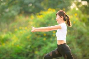 una bella donna asiatica si sta riscaldando, per rendere flessibili i muscoli prima di andare a fare jogging foto