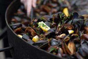 primo piano di cozze cotte in un festival di cibo di strada, pesce pronto da mangiare fotografato con messa a fuoco morbida foto