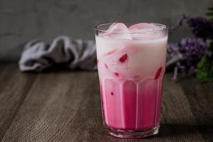 bevanda fredda al latte rosa freddo in vetro trasparente su sfondo grigio. latte tailandese foto