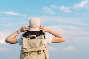 viaggiatore donna con zaino che tiene il cappello e guardando il cielo blu, il concetto di viaggio, lo spazio per il testo e il momento atmosferico foto