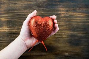 persona Tenere un' fatto a mano rosso cuore nel sua mani. amore. il 14 di febbraio. San Valentino giorno. foto