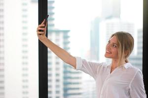 ritratto di una giovane donna attraente che fa foto selfie su smartphone in un moderno edificio per uffici sullo sfondo