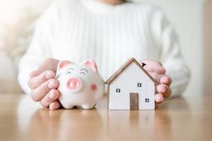 donna con salvadanaio e futuro concetto di casa di risparmio e prestito di denaro per la casa. affittare o acquistare una nuova casa risparmiando denaro nel salvadanaio. foto