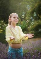 bellissimo poco ragazza nel un' campo con lavanda. foto