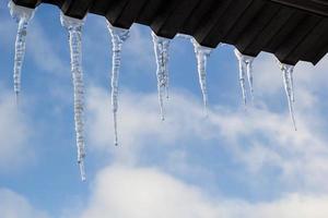 ghiaccioli sospeso su tetto a inverno. naturale ghiaccio formazione di ghiaccio cristalli sospeso su tetto bordo a inverno foto