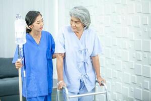 asiatico infermiera assistere anziano paziente provando per camminare con soluzione salina a Ospedale, assistenza sanitaria e medicina concetto. foto