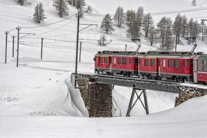 rosso treno nel il neve nel svizzero Alpi foto