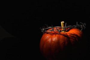 arancia zucca con un' ghirlanda di spinato filo, un' corona di spine, su un' nero sfondo. Halloween concetto. copia spazio. foto