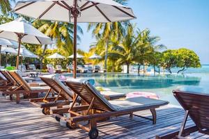 ombrelli e sedie in giro all'aperto nuoto piscina nel ricorrere Hotel per vacanza tempo libero stile di vita. lusso destinazione concetto, sala avvicinamento panoramico sotto palma alberi, relax, tranquillo vibrazioni foto