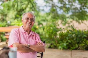 ritratto asiatico anziano uomo 83 anni vecchio con trentadue denti Sorridi seduta all'aperto nel il giardino. foto