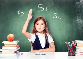 contento e carino adolescente scolara raccolta mano nel aula foto