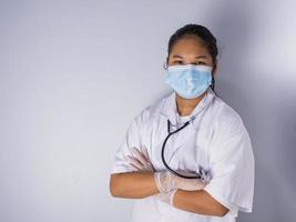 studio ritratto di un' femmina medico indossare un' maschera in piedi su un' bianca sfondo Là era un' leggero leggero su il suo viso. foto