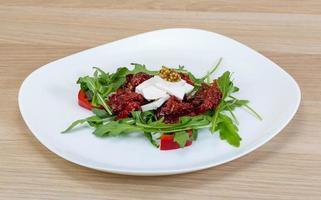 insalata con secco pomodoro su il piatto e di legno sfondo foto