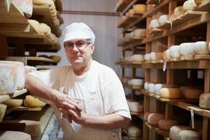 formaggio creatore a il Conservazione con scaffali pieno di mucca e capra formaggio foto