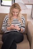 donna seduta su divano con mobile Telefono foto