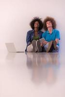 multietnico coppia seduta su il pavimento con un' il computer portatile e tavoletta foto