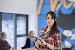 ritratto di giovane attività commerciale donna a ufficio con squadra nel sfondo foto