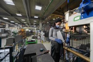 tacchino, 2022 - donna Lavorando nel il metallo industria nel il produzione di nuovo macchine indossa un' viso maschera durante opera dovuto per il coronavirus pandemia foto