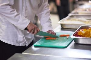 capocuoco nel Hotel cucina fetta verdure con coltello foto