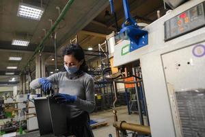 donna Lavorando nel il metallo industria nel il produzione di nuovo macchine indossa un' viso maschera durante opera dovuto per il coronavirus pandemia foto