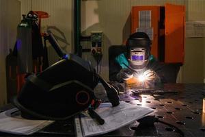 professionale saldatore esegue opera con metallo parti nel fabbrica, scintille e elettricità. industria lavoratore striscione. foto