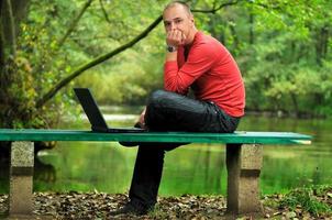 giovane uomo d'affari nel rosso camicia Lavorando su il computer portatile foto