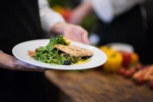 capocuoco mani Tenere piatto di fritte salmone pesce filetto foto