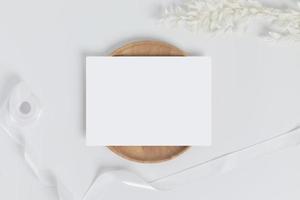 saluto carta o invito carta con bianca asciutto fiore le foglie su legna piatto o vassoio nel bianca sfondo, superiore Visualizza foto