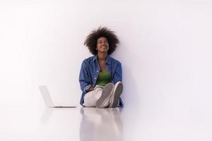 africano americano donna seduta su pavimento con il computer portatile foto