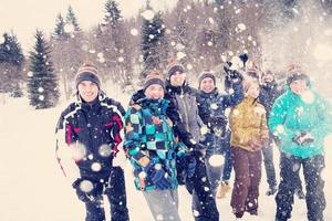 gruppo di giovane persone lancio neve nel il aria foto