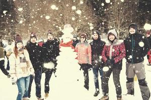 gruppo portait di giovane persone in posa con pupazzo di neve foto