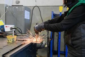 un' donna Lavorando nel il moderno metallo produzione e in lavorazione industria saldature il Prodotto e prepara esso per un' cnc macchina foto