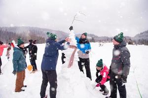 gruppo di giovane persone fabbricazione un' pupazzo di neve foto