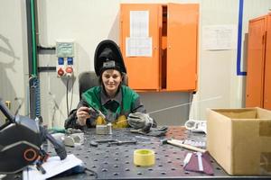 un' donna occupato nel un' moderno fabbrica per il produzione e in lavorazione di metalli nel un' opera uniforme saldature metallo materiale foto