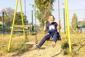 contento piccolo ragazza avendo divertimento su un' swing nel natura. foto