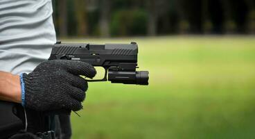 pistola Tenere nel mani di bandito a il tiro club, morbido e selettivo messa a fuoco su pistola, concetto per tiro sport, guardia del corpo, sicurezza addestramento, mafie, gangster e se stesso protezioni. foto