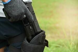 pistola Tenere nel mani di bandito a il tiro club, morbido e selettivo messa a fuoco su pistola, concetto per tiro sport, guardia del corpo, sicurezza addestramento, mafie, gangster e se stesso protezioni. foto