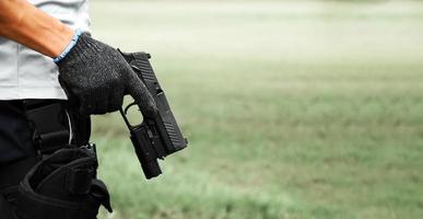 pistola Tenere nel mani di bandito a il tiro club, morbido e selettivo messa a fuoco su pistola, concetto per tiro sport, guardia del corpo, sicurezza addestramento, mafie, gangster e se stesso protezioni. foto