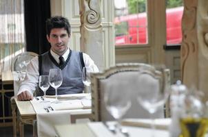 giovane uomo seduta e in attesa cibo a elegante ristorante foto