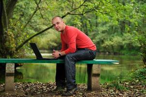 giovane uomo d'affari nel rosso camicia Lavorando su il computer portatile foto