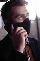 attività commerciale uomo indossare coronavirus medico viso maschera mentre utilizzando smartphone foto