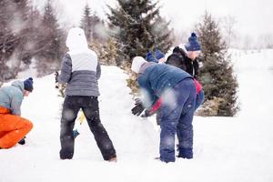 gruppo di giovane persone fabbricazione un' pupazzo di neve foto